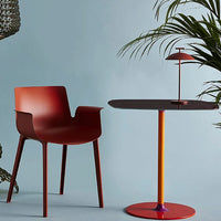 Modern red chair and round table with vibrant orange and purple accents against a soft blue background.