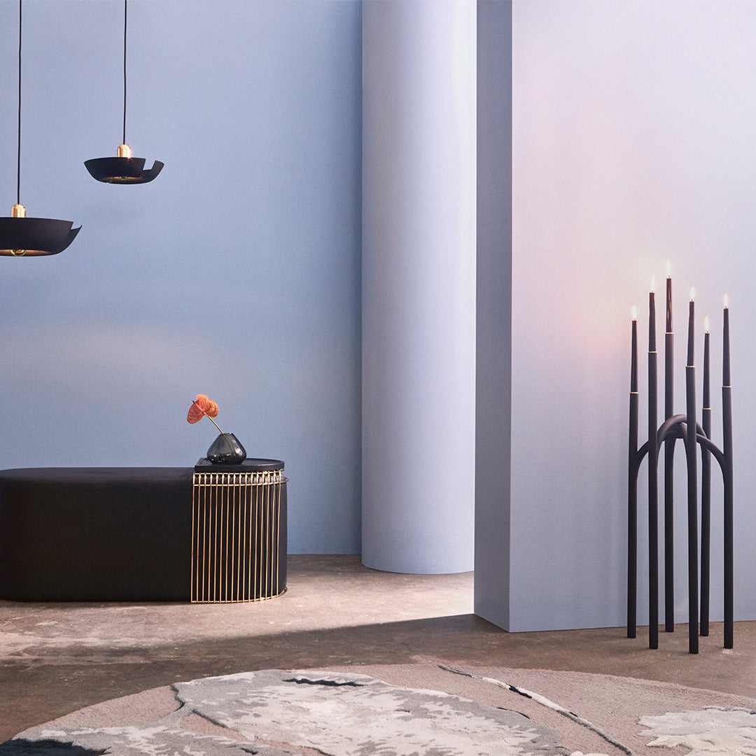 Modern decor featuring blue walls, black furnishings, gold accents, and a textured, pastel rug pattern.