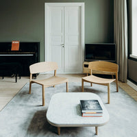 Light wooden chairs, gray rug, white marble table, and muted green walls create a serene modern aesthetic.