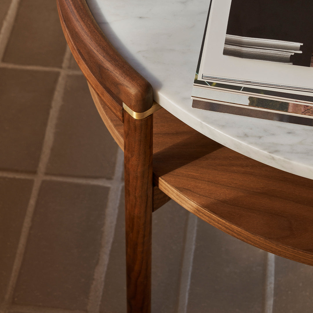 Walnut wood table with a white marble top and gold accents, featuring a smooth, brown finish and subtle textures.