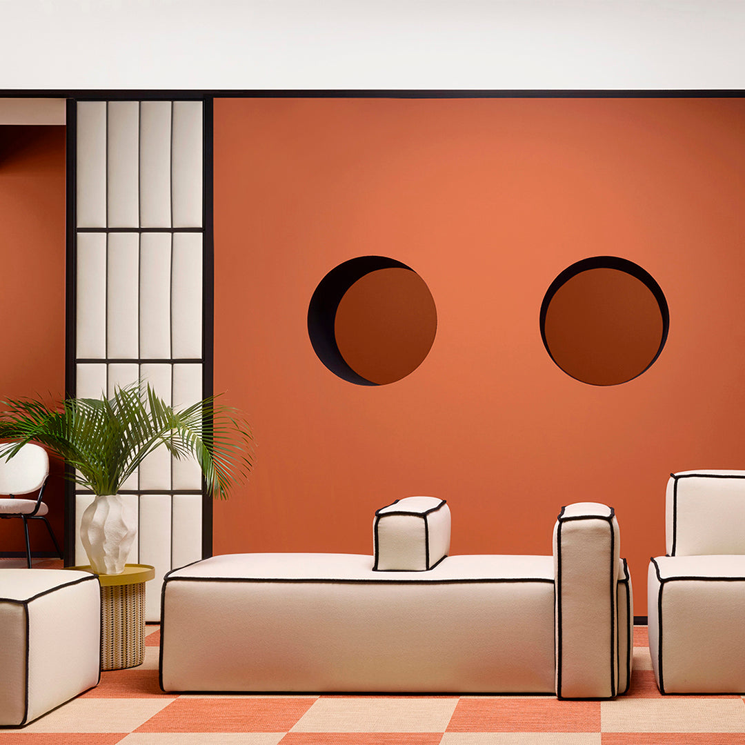 Modern indoor space with a terracotta wall, white furniture featuring black edging, and a textured checkered floor.
