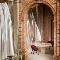 Stylish burgundy chairs and silver drapes contrast with warm brick tones in a refined interior setting.