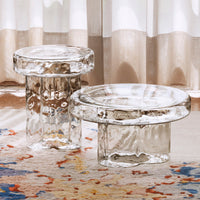 Clear glass side tables with a textured surface, showcasing a modern design and vibrant patterned rug underneath.