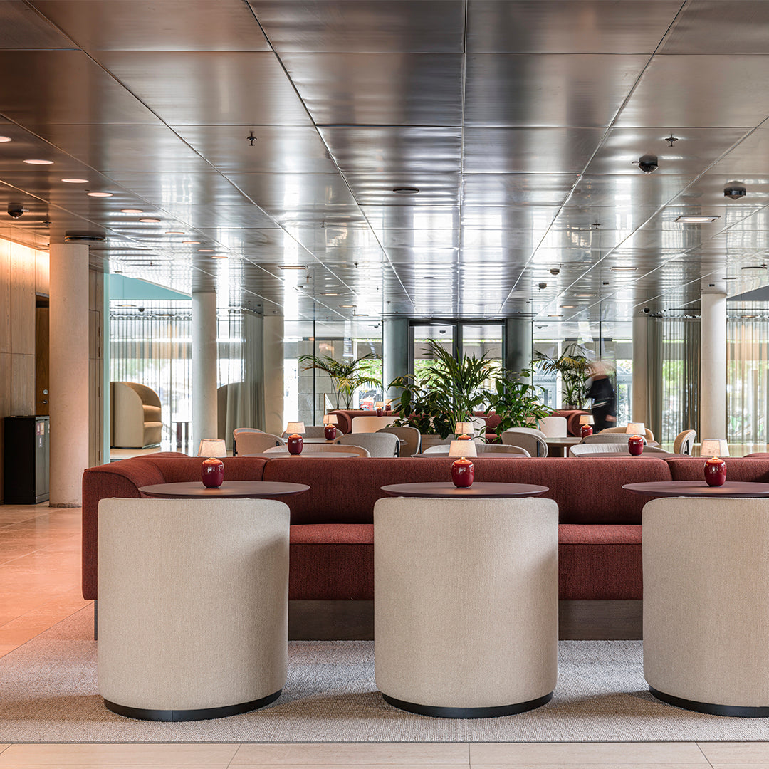 Red and beige furniture pieces with smooth textures in a modern, reflective lounge setting.