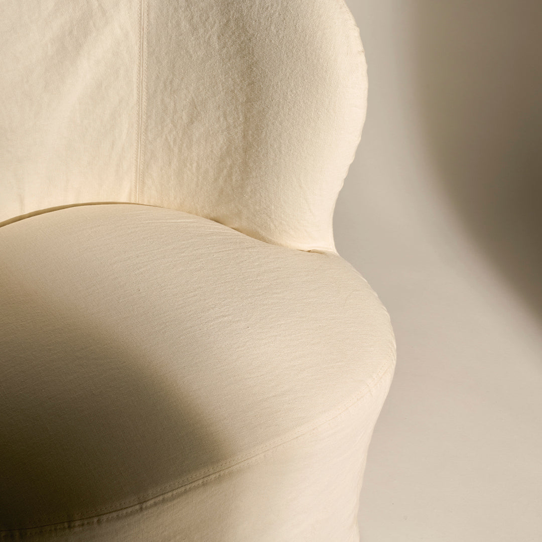 Cream-colored upholstered chair with a smooth, subtle texture and soft, rounded contours.