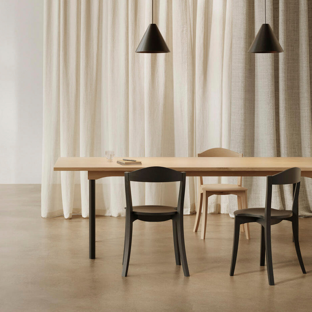 Modern dining room featuring a wooden table, black chairs, and neutral-patterned curtains in soft beige tones.