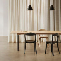 Modern dining room featuring a wooden table, black chairs, and neutral-patterned curtains in soft beige tones.