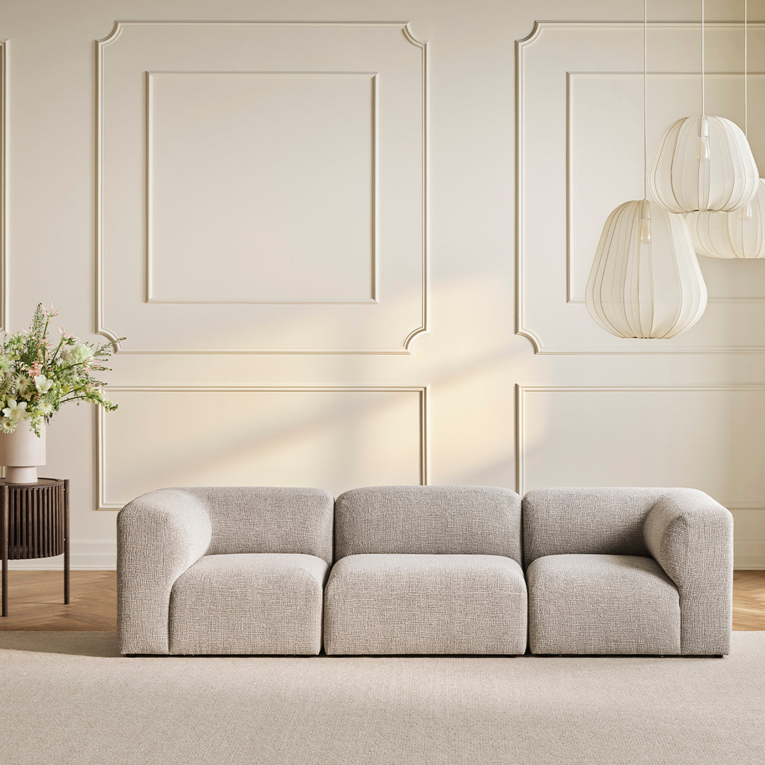 Neutral beige couch with a soft, textured fabric, featuring a sleek, modern silhouette against a light backdrop.