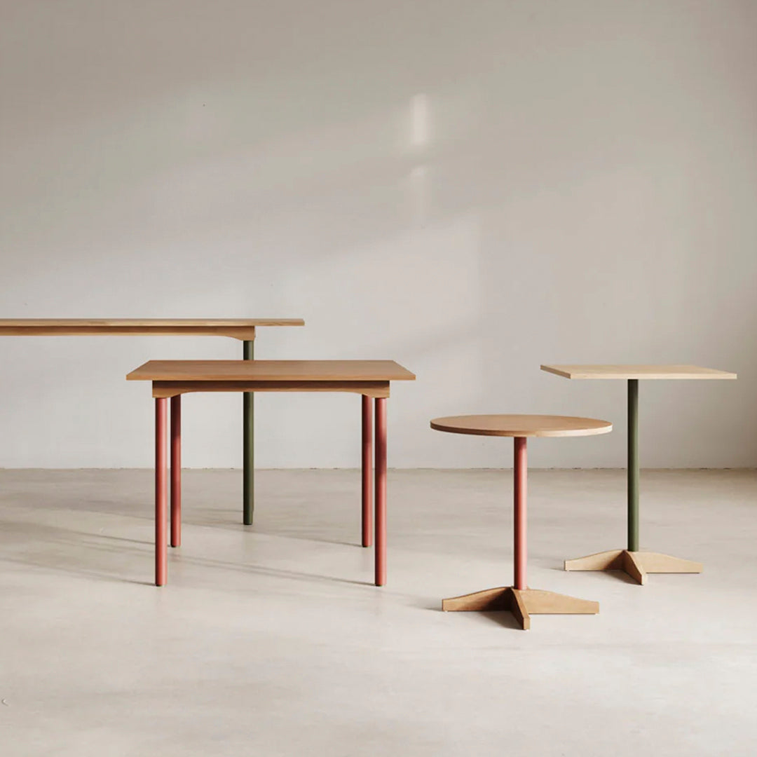 Modern tables in earthy tones of brown, red, and green with clean, minimalist lines and unique shapes.