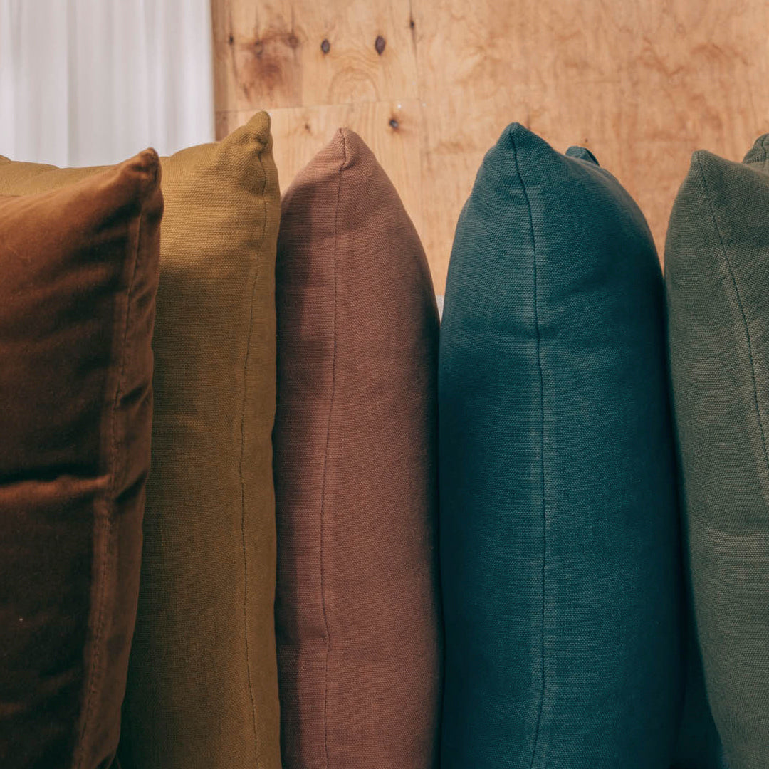 Colorful pillows in rich hues: olive green, deep teal, earthy brown, mustard yellow, and soft beige. Perfect for home decor.