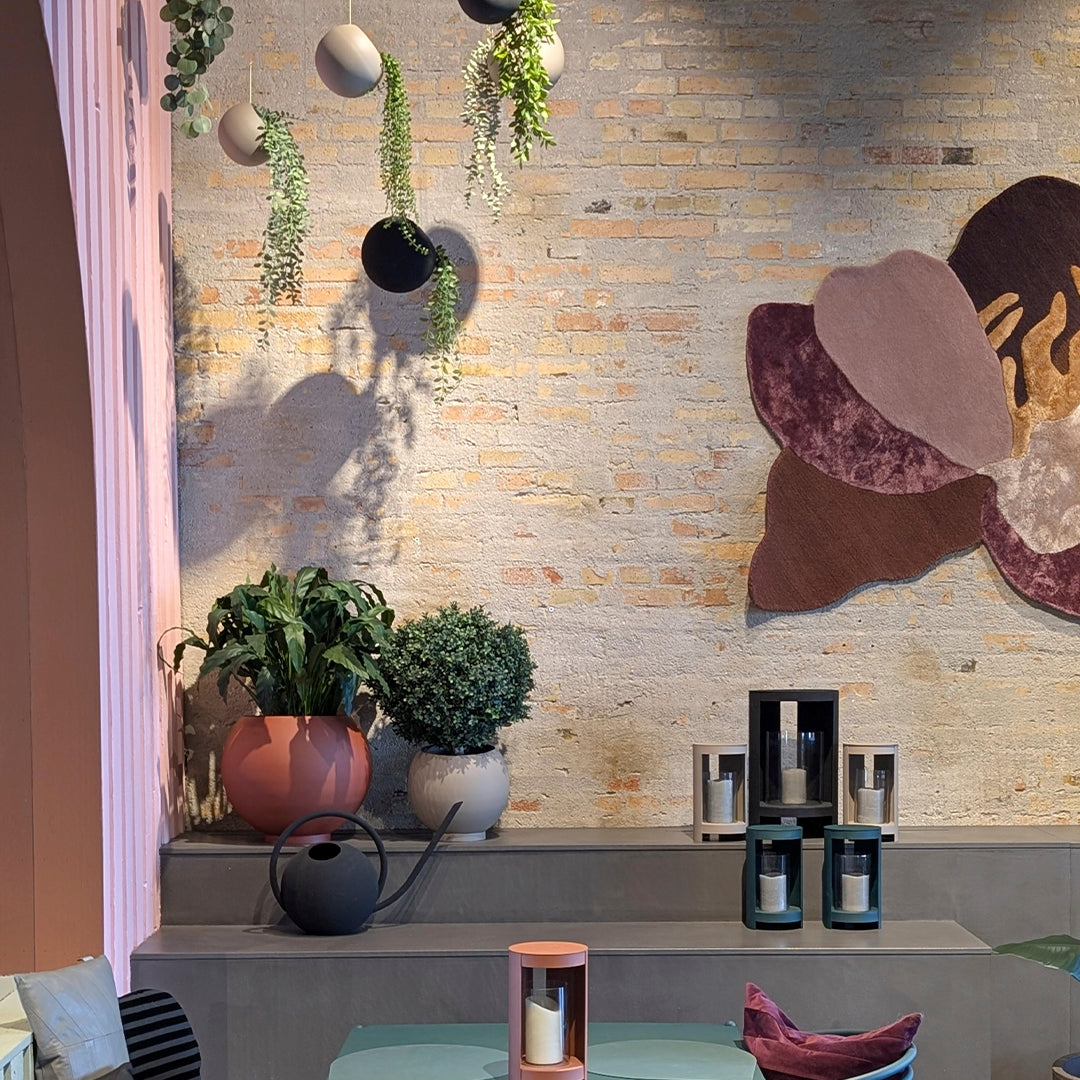 Colorful wall decor with earthy tones, green plants, and pastel planters against a textured, neutral backdrop.