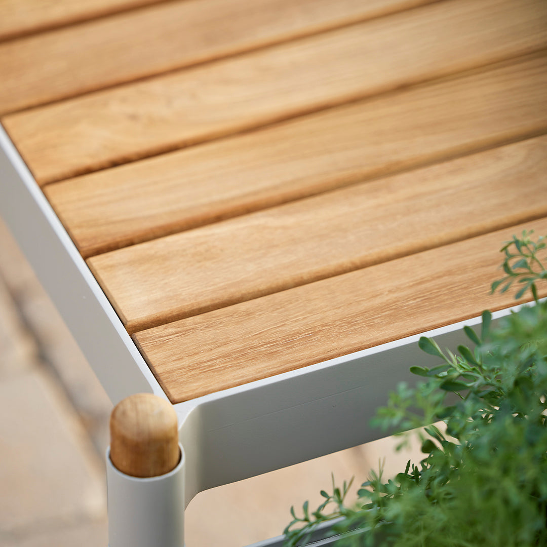 Light wood slats with a natural finish, complemented by a sleek white frame and green foliage.