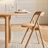 Natural wood dining table with light tan chair and beige textured rug, creating a warm and inviting ambiance.