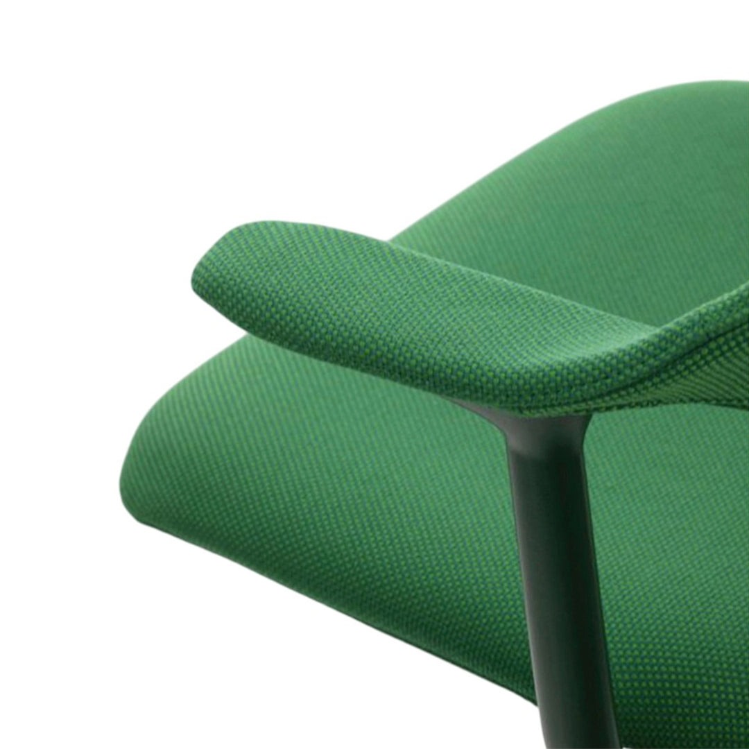 Close-up of a textured green fabric chair with subtle darker green patterns and a sleek black frame.