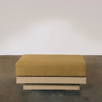 Yellow upholstered ottoman on a light wooden base, featuring a minimalist design and modern aesthetics.