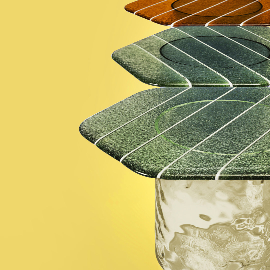 Colorful glass coasters in orange, dark green, and light green with white stripe patterns against a yellow background.