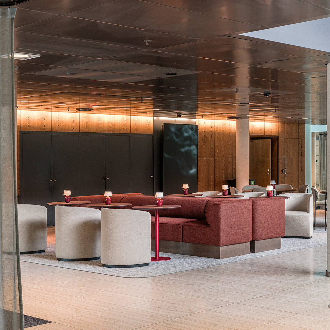 Modern lounge featuring beige and reddish-brown furniture with sleek metal accents and subtle lighting.