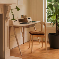 Light wood desk with a natural finish, paired with a brown upholstered chair against a warm wooden floor.