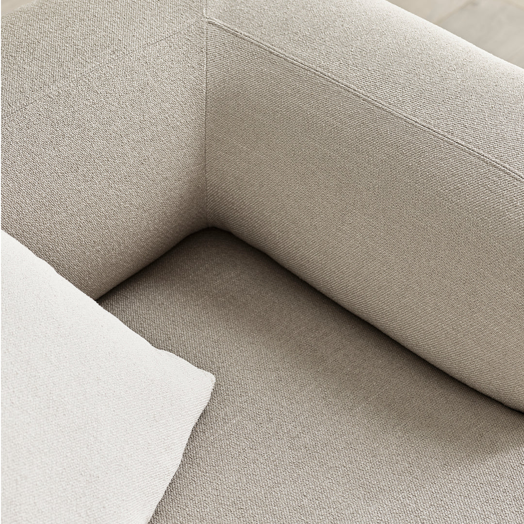 Light beige textured fabric of a modern sofa, featuring subtle patterns and a cozy neutral cushion accent.