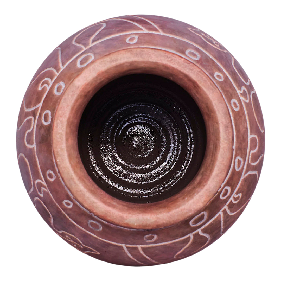Top view of a round, earthy-toned pot with intricate white patterns and a glossy dark brown interior.