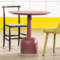 "Round pink table, black and gray chair, yellow chair, and vibrant yellow backdrop create a colorful modern setting."