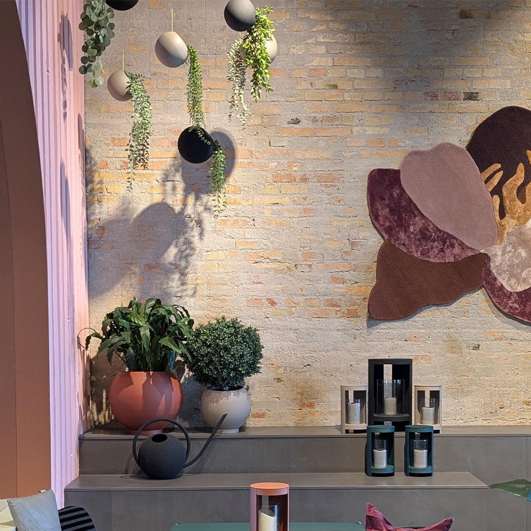 Colorful wall decor with geometric patterns, green plants, and pastel planters in a modern setting.
