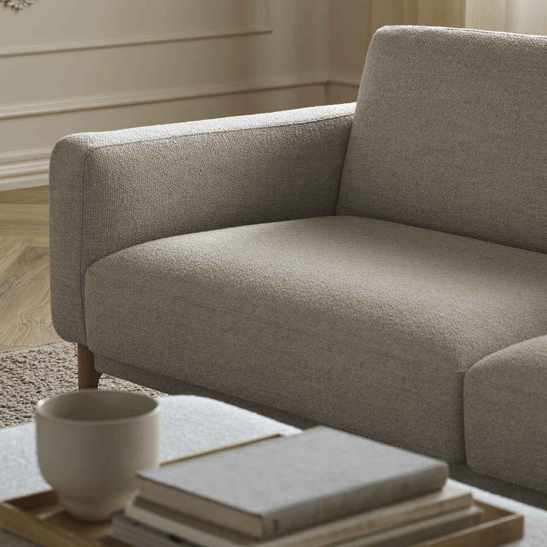 Light gray sofa with a textured fabric and natural wood legs, displayed with a neutral-toned coffee table setup.