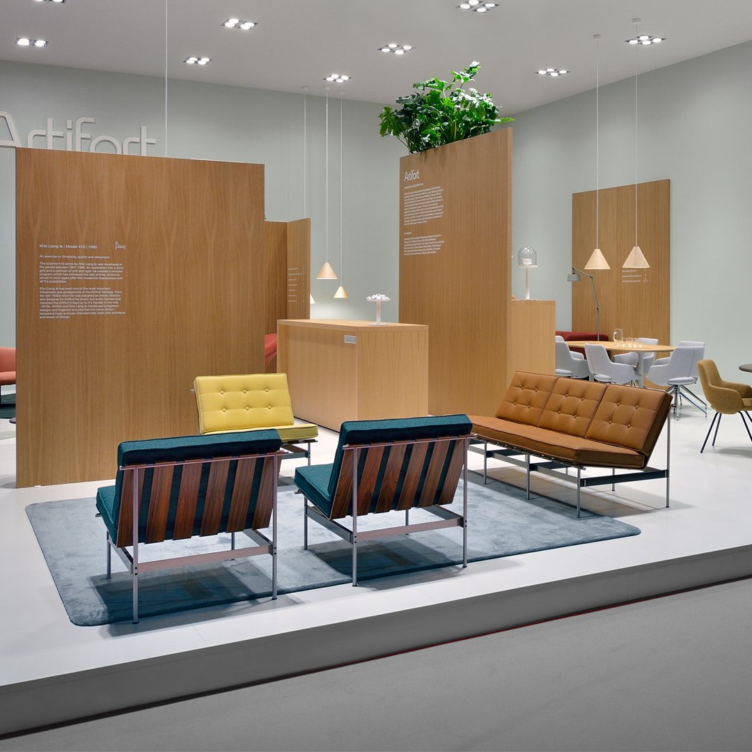 Modern lounge area with blue, yellow, and orange seating on a soft blue rug against a neutral backdrop.