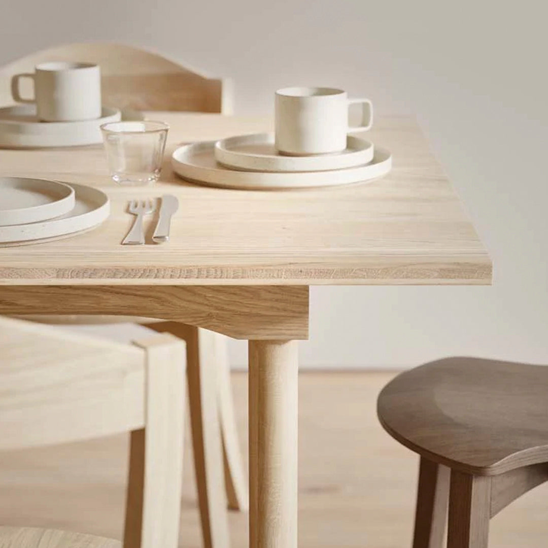 Natural wood dining table with light beige tableware and soft cream accents, creating a minimalist and elegant look.