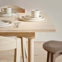 Natural wood dining table with light beige tableware and soft cream accents, creating a minimalist and elegant look.