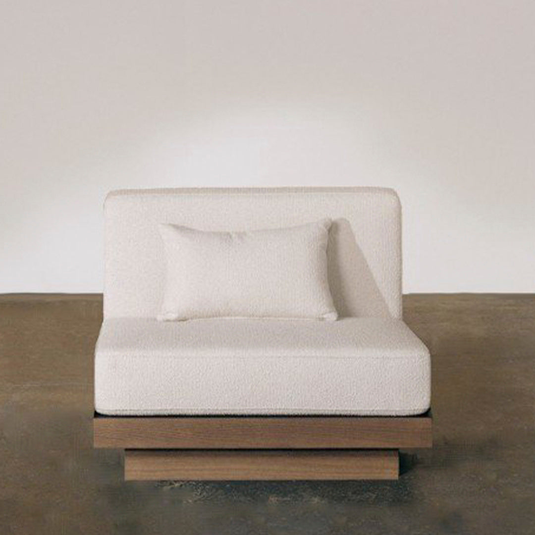 Beige upholstered chair with a minimalist design and a wooden base, featuring a matching rectangular throw pillow.