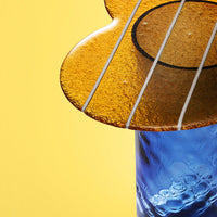 Amber guitar-shaped decor on a blue base against a bright yellow background, showcasing vibrant colors and elegant patterns.