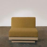 Yellow mustard upholstered chair with a minimalist wood base, set against a neutral background. Modern design.
