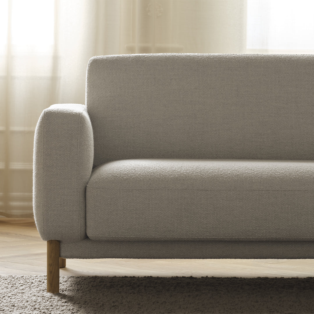 Light gray upholstered sofa with clean lines and wooden legs, set against a soft, neutral background.