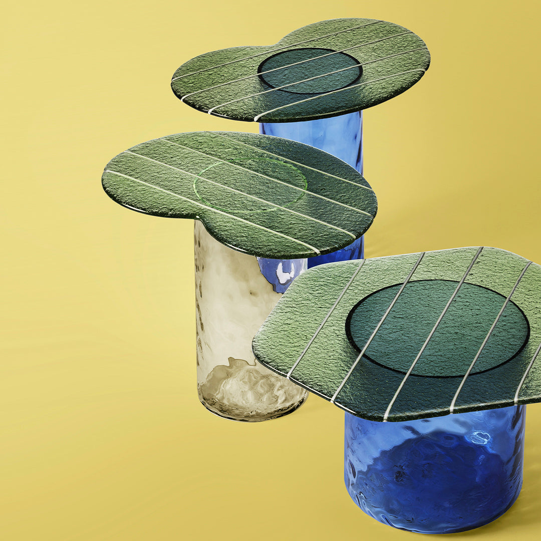 Green textured tops with circular patterns on blue and transparent glass bases against a yellow background.