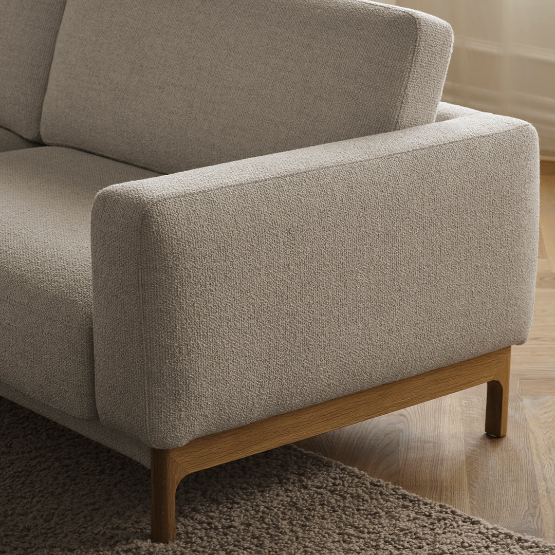 Light beige textured upholstery with natural wood legs, featuring a minimalist design and modern aesthetic.