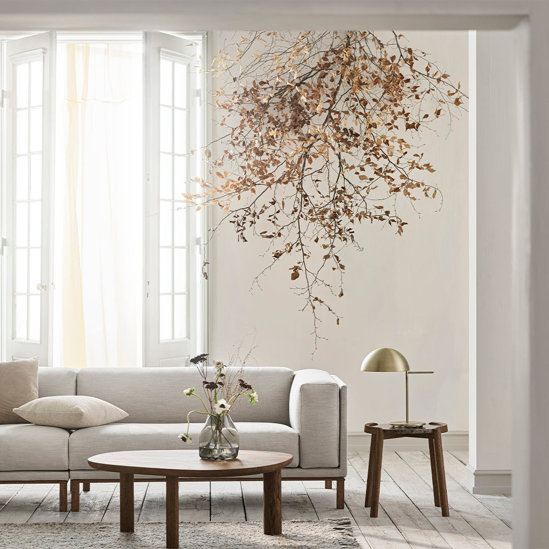 Neutral beige sofa with light wooden coffee table, accented by soft earth tones and a subtle floral arrangement.