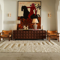 "Textured white rug with beige stripes in a modern living room featuring earthy tones and vibrant artwork."
