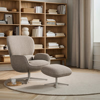 Minimalist beige armchair and ottoman, featuring a textured pattern, set against light wood and soft neutrals.