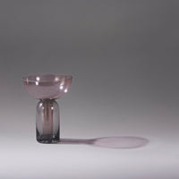 Translucent pink bowl atop a smoky gray glass base, creating elegant contrast and soft shadows.