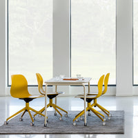 Yellow modern chairs around a minimalist white table on a gray rug, set against large windows.