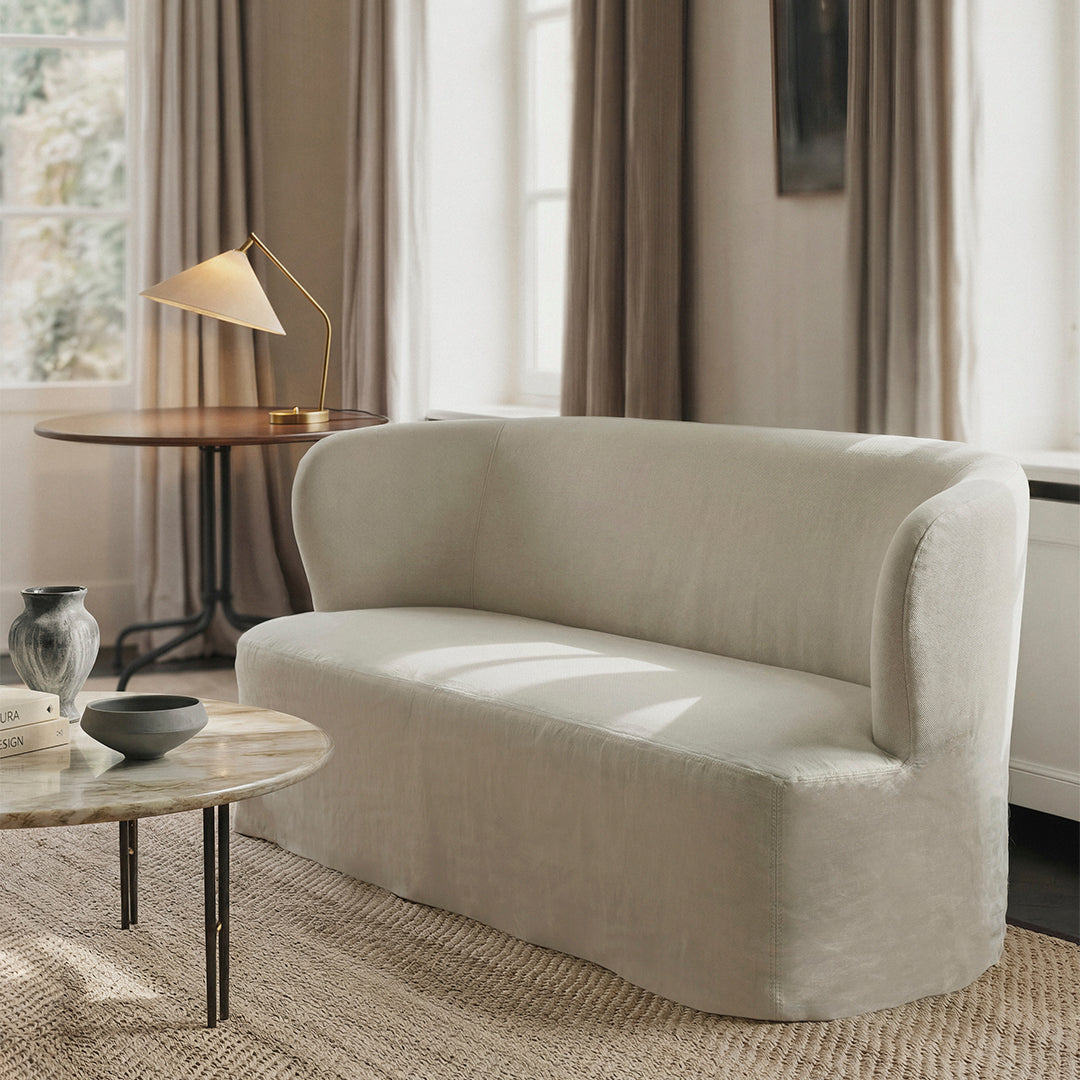 Light beige curved sofa with soft texture, complemented by neutral tones in a cozy, modern living space.