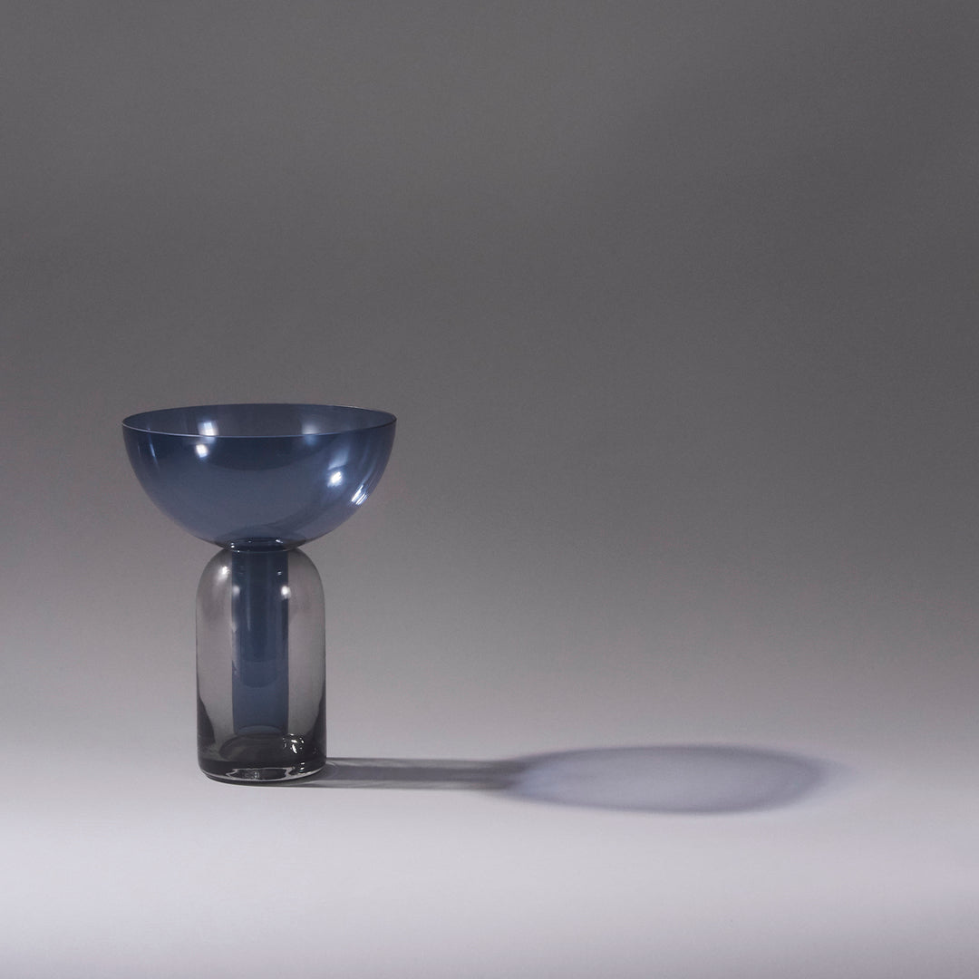 Modern glass vase featuring a blue bowl top and smoky gray base, set against a minimalist background.