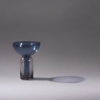 Modern glass vase featuring a blue bowl top and smoky gray base, set against a minimalist background.