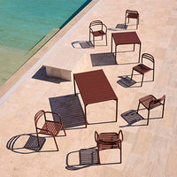 Rust-colored outdoor furniture with striped patterns, arranged around a clear blue pool on a sunlit patio.