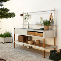 "Modern outdoor kitchen in soft gray and natural wood tones, featuring sleek lines and woven basket accents."