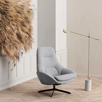 Gray upholstered chair with a smooth finish, surrounded by natural textures and neutral-toned wall decor.