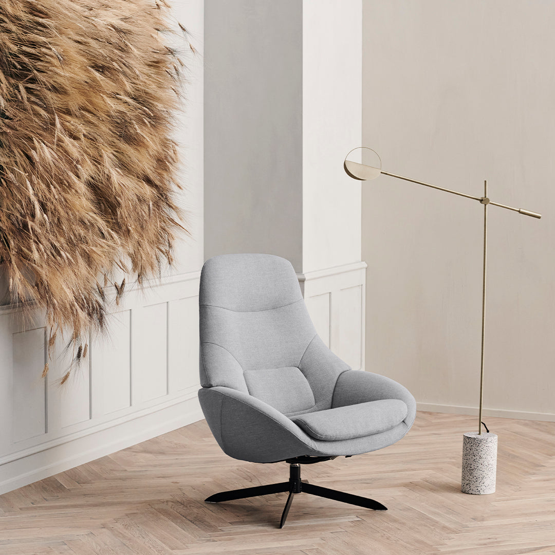 Light gray swivel chair with smooth fabric and minimalist design, accented by warm wood and natural textures in the background.