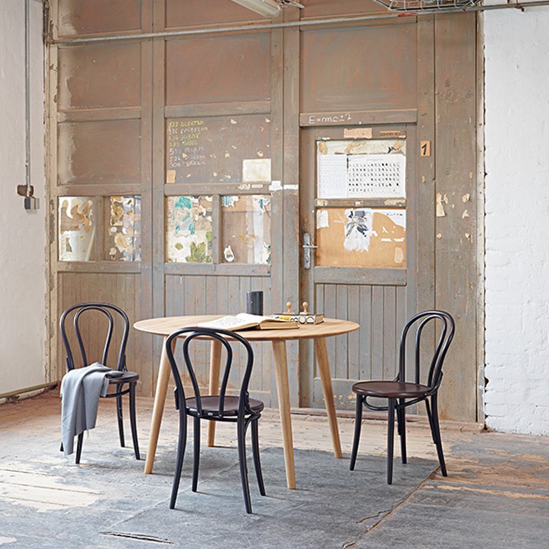 Scandinavian-style dining set with natural wood table and black chairs, featuring a minimalist aesthetic in a neutral backdrop.
