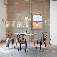Scandinavian-style dining set with natural wood table and black chairs, featuring a minimalist aesthetic in a neutral backdrop.